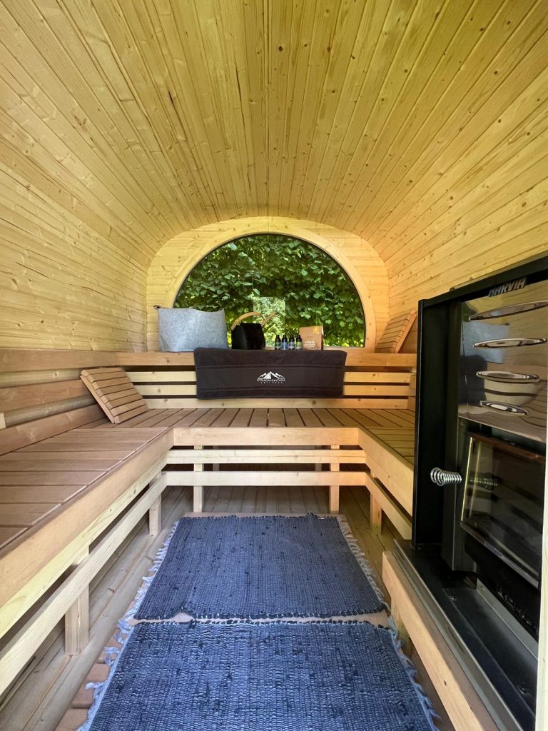 Innenraum einer Outdoor Quadro Sauna mit Holzofen, Sitzbank in U-Form, zwei Ebenen und Panoramafenster