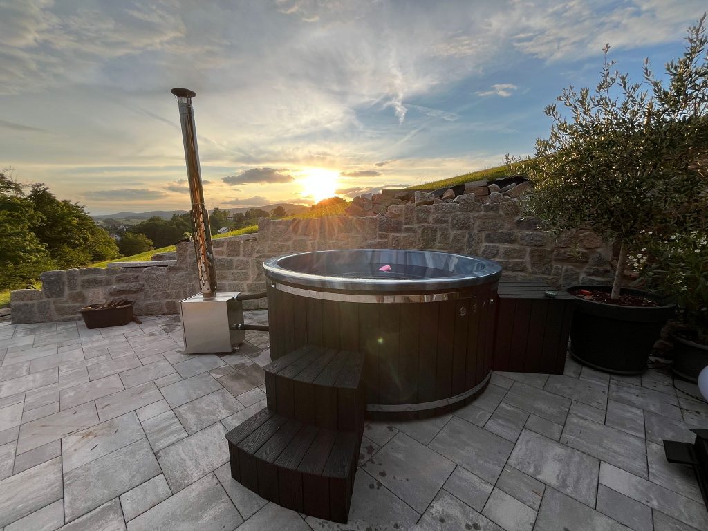 Hot Tub Whirlpool mit externem Ofen auf einer Terrasse bei Sonnenuntergang